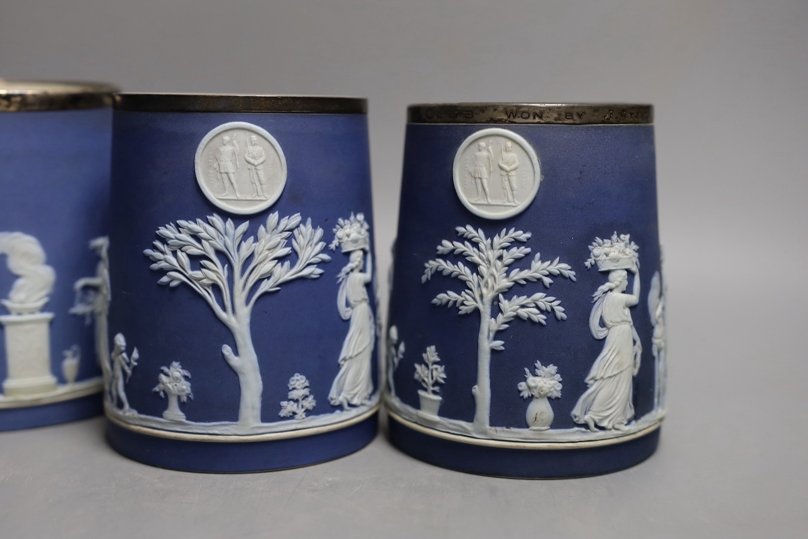 Five Wedgwood for Elkington & Co. blue jasper rifle or shooting club trophy mugs, 12.5cm high some with silver mounted rims, including Richmond rifle club, London Scottish etc.